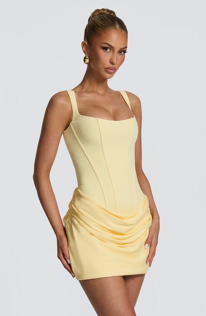 Three-quarter view of the pale yellow dress, showing the structured seaming of the bodice and the gathered drape at the hips. 24