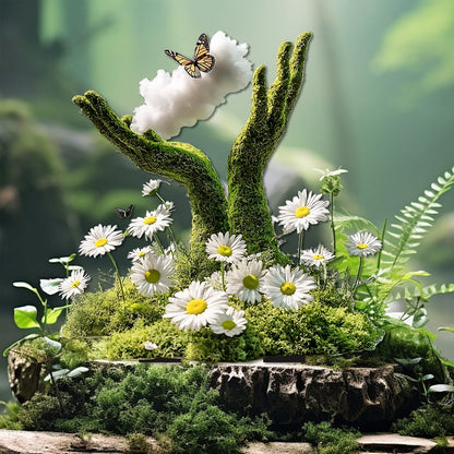Moss-covered hands reaching up beside a white cloud and butterfly, set among daisies, ferns and moss on a rocky base. 22