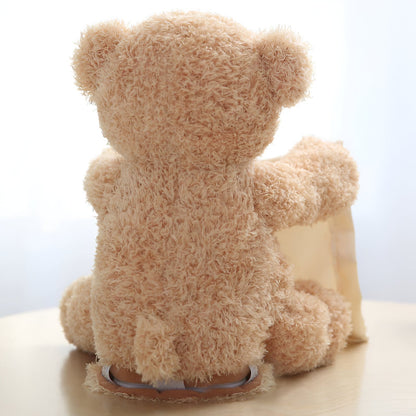 Back view of the fluffy beige teddy bear seated on a table, its arm stretched towards the cream cloth. 4
