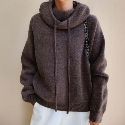 Front view of the dark brown knit jumper with a cowl neck, long drawstrings and a ribbed hem 7