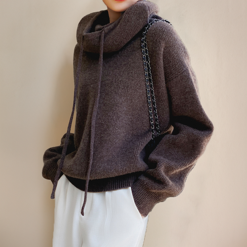 Brown knit jumper with drawstring roll neck, worn with white trousers and a chain-strap bag 7