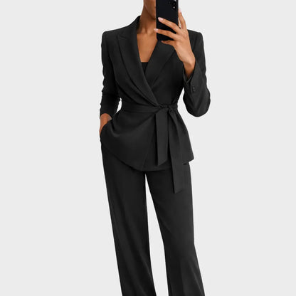 Black version of the tie-waist wrap blazer and matching wide-leg trousers, worn by a model holding a phone. 3