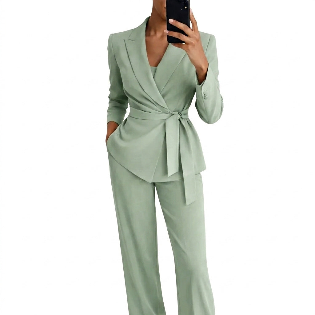 Model in the sage green wrap-front blazer with tie belt and wide-leg trousers, holding a phone in a mirror selfie. 1