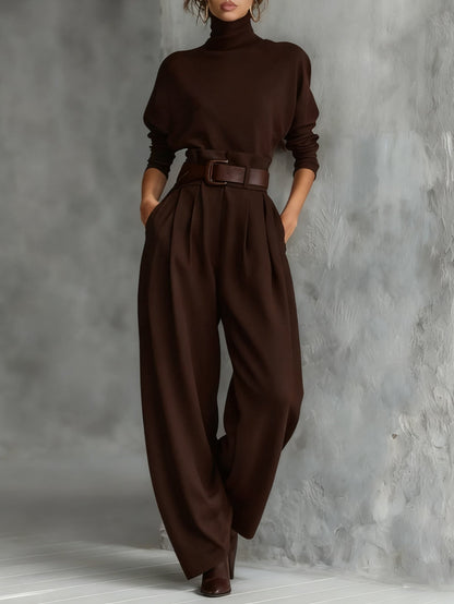 Model in the dark brown set with matching brown belt, hands in pockets, leaning near a textured wall 5