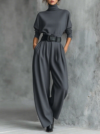 Model wearing the dark grey set with a black belt, pleated wide leg trousers and ankle boots 7