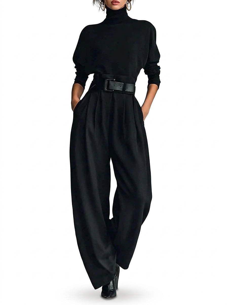 Model in black high-neck top and pleated wide leg trousers with a black leather belt, front view 1