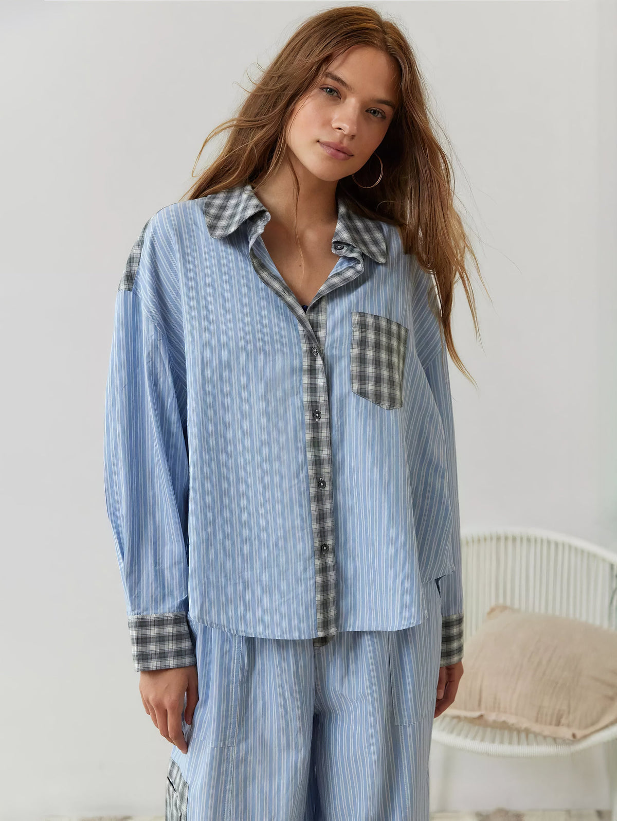 Front view of the blue striped pyjama shirt buttoned up, with grey check collar, pocket, placket and cuffs, worn with matching trousers. 5