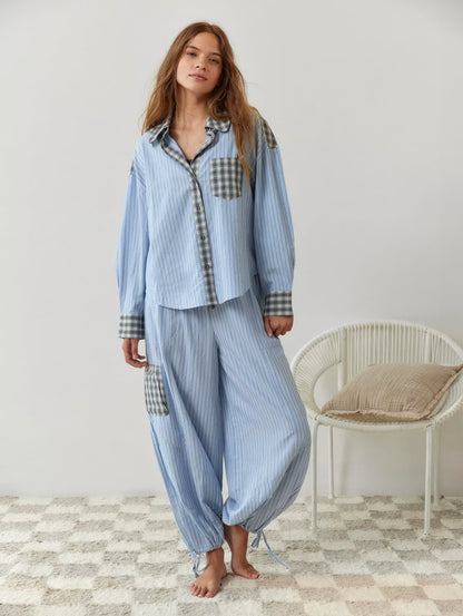 Full-length shot of the blue striped pyjama set on a barefoot model, showing wide trousers with grey check cargo pocket and tied ankles. 7