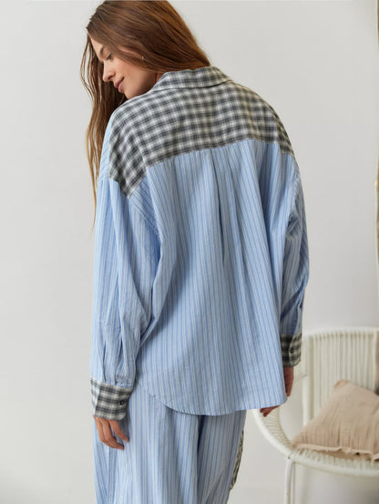 Back view of the blue striped pyjama shirt, with a grey check yoke, collar and cuffs, worn with matching striped trousers. 9