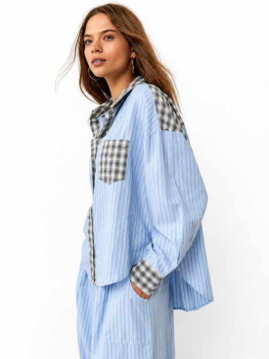 Model in the blue striped pyjama shirt with grey check pocket, collar and shoulder panels, one hand in a trouser pocket, shown in side profile. 1