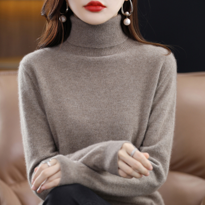 Taupe roll-neck jumper on a seated model, showing the ribbed collar and cuffs and the soft, slightly fluffy knit. 13
