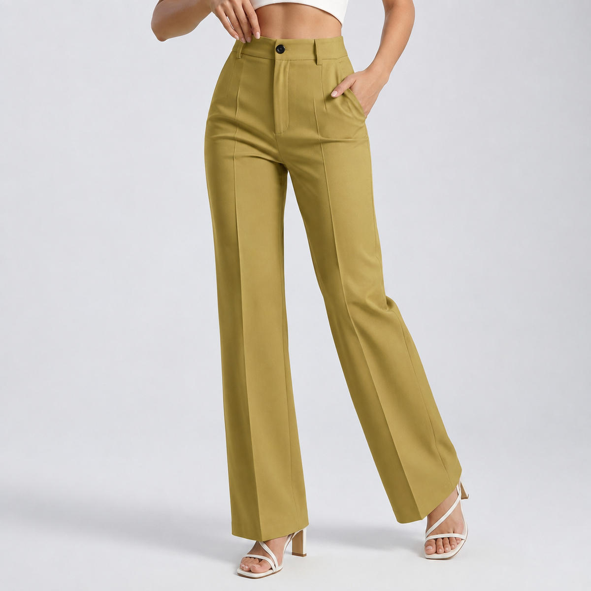 Model wearing mustard-yellow trousers with front pleat creases, one hand in pocket, with white strappy heels 21