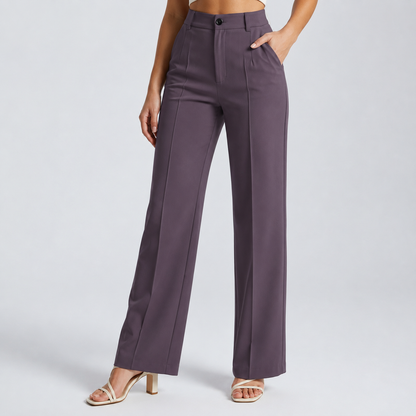 Model wearing dusky purple-grey trousers with a button waist and pintucks, hand in pocket, with cream heeled sandals 22