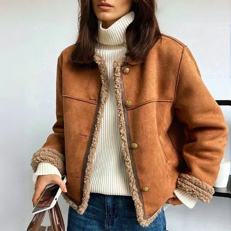 Model wears the tan suede jacket open over a cream ribbed polo neck and jeans, holding a phone 1