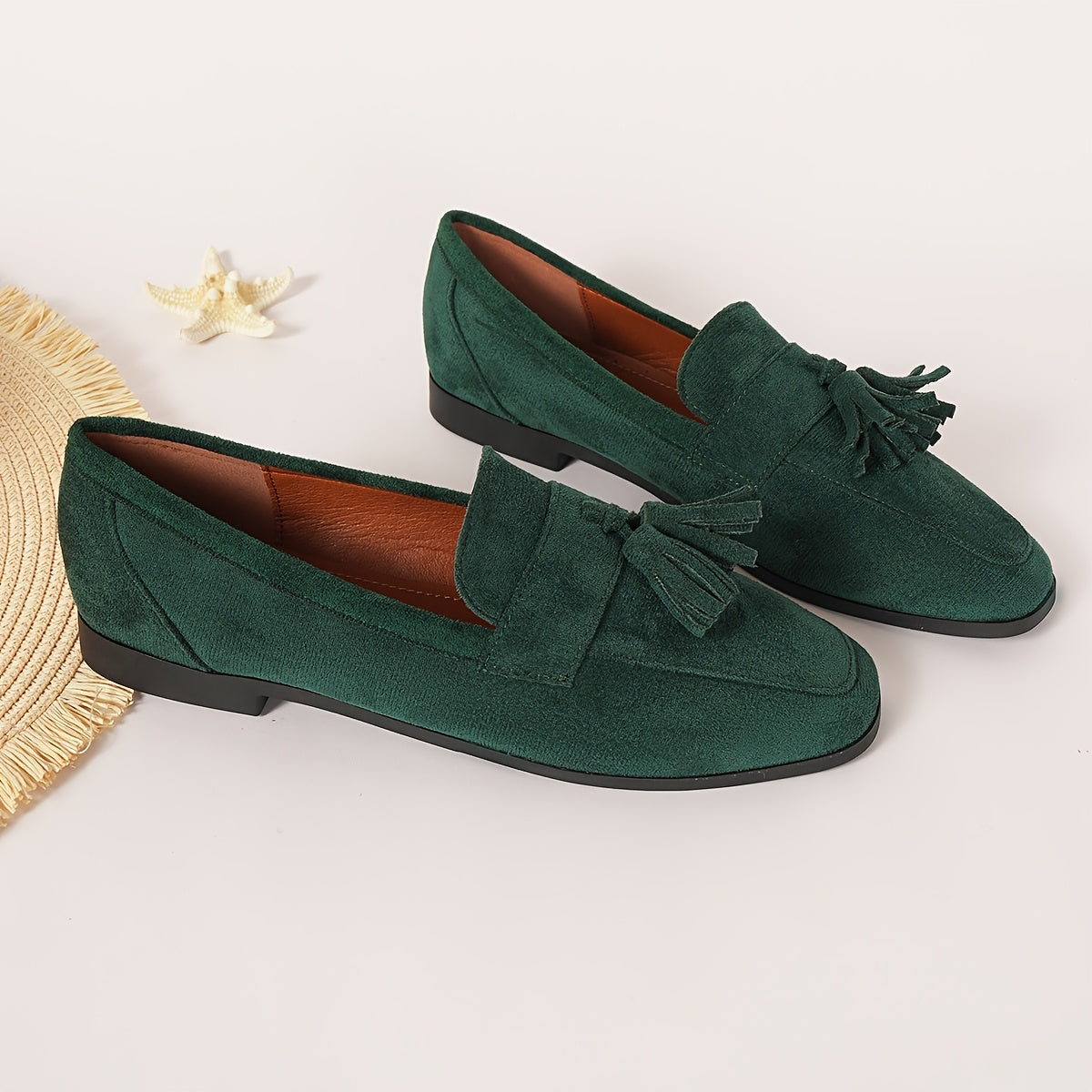 Pair of green tasselled loafers beside a straw mat and a starfish, tan lining visible 12