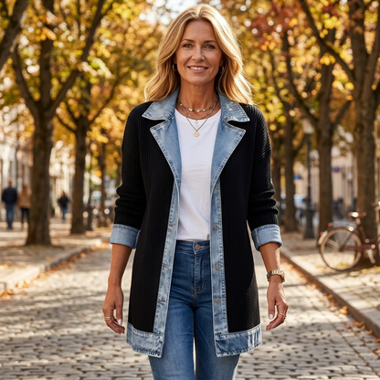 Smiling model in the black ribbed knit coat with denim trim, walking down an autumn cobbled street 1