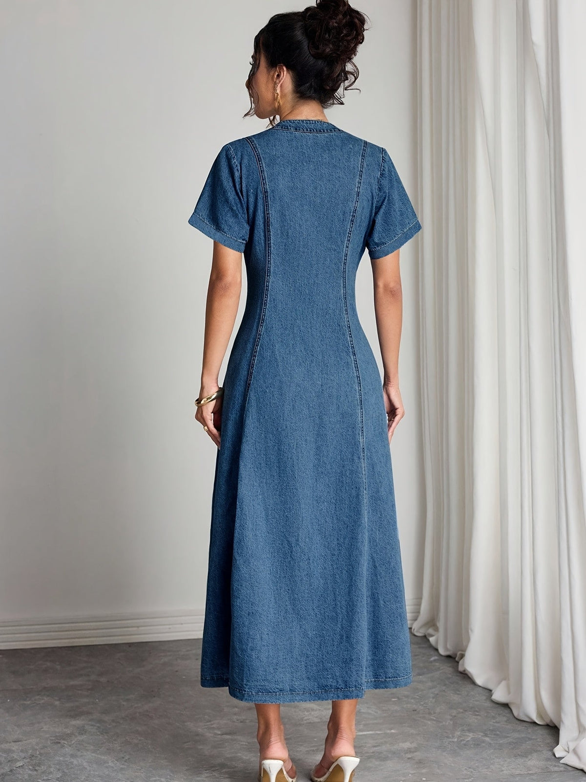Back view of the short-sleeved dress on a model, showing panelled seams and a flared skirt 2