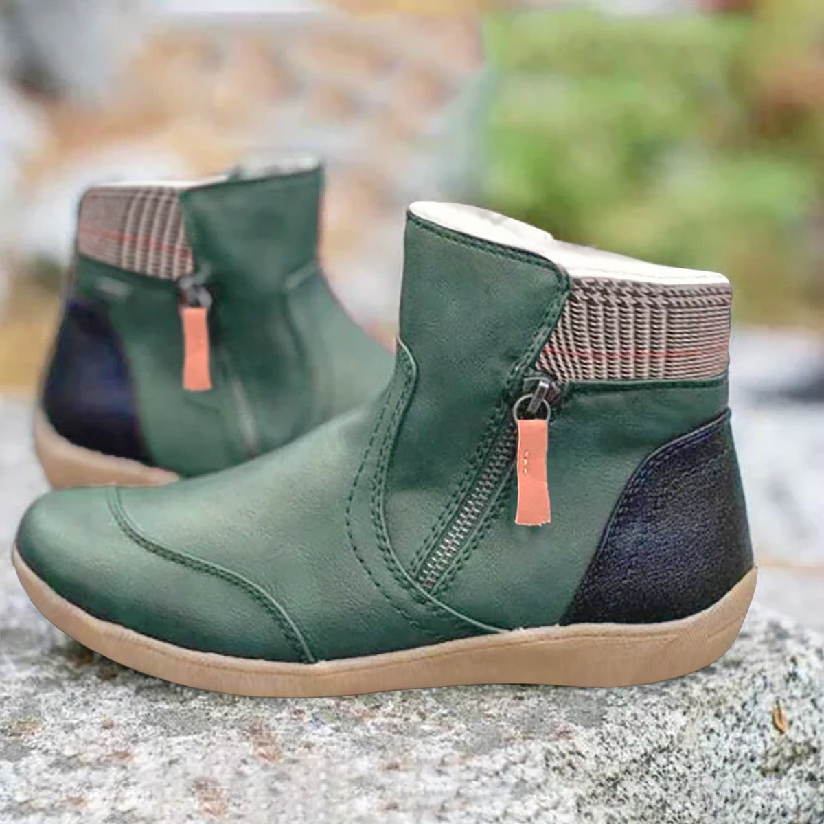 Pair of dark green leather ankle boots with side zip, checked collar and black heel panel, standing on a rock. 1