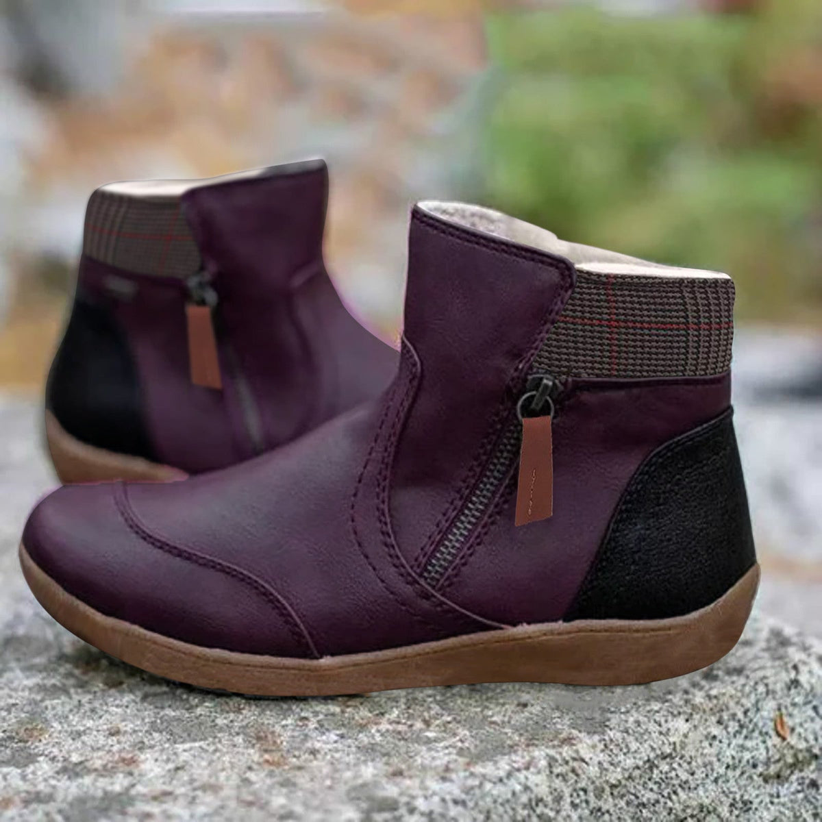 Pair of purple leather ankle boots with side zip, checked collar and black heel panel, standing on a rock. 4