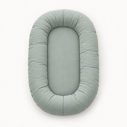 Empty sage green oval lounger seen from above, showing its padded rim and flat centre 8