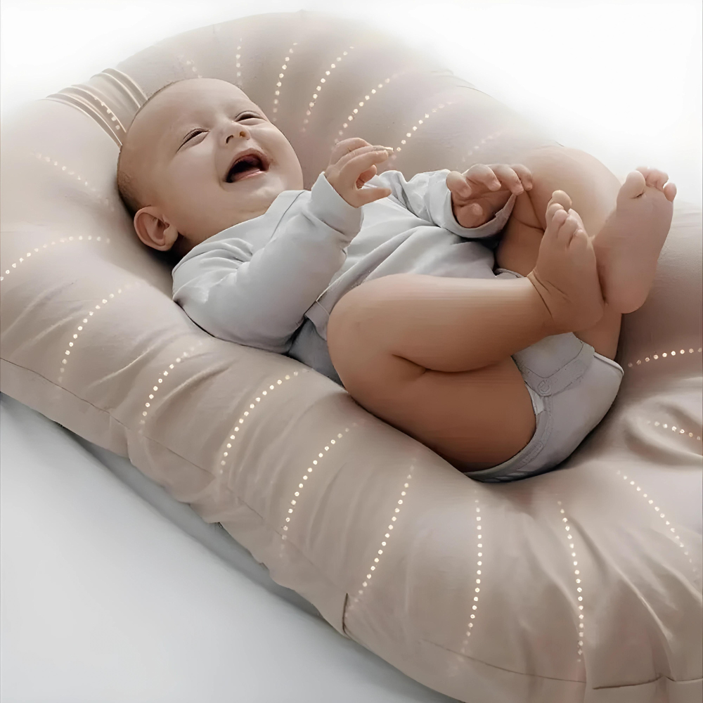 Close-up of a giggling baby kicking up its legs on a beige lounger with dotted stitching 2