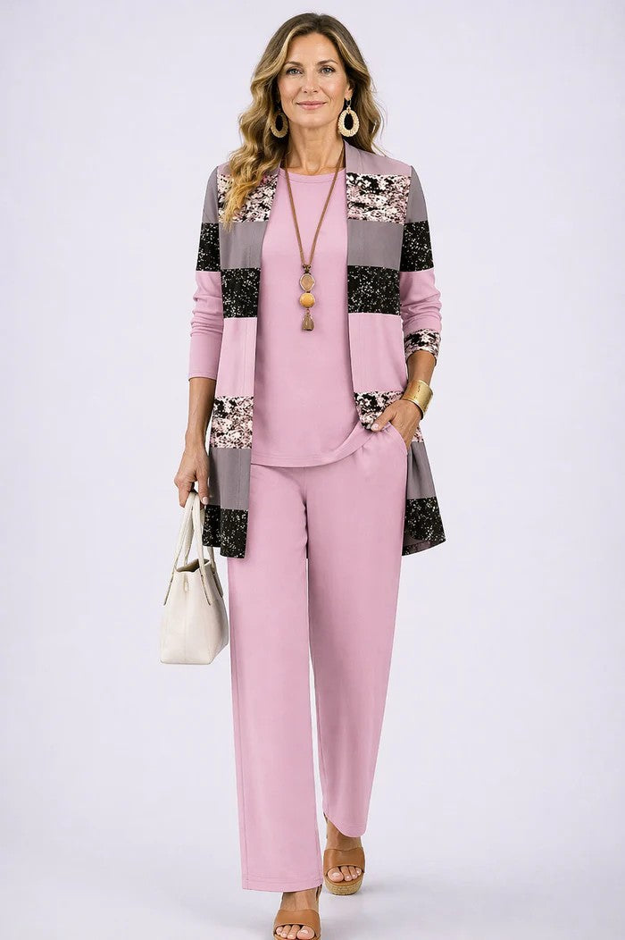 Model in the pink set, the open cardigan in colour-block stripes of pink, grey and speckled print, over a plain top and trousers. 12