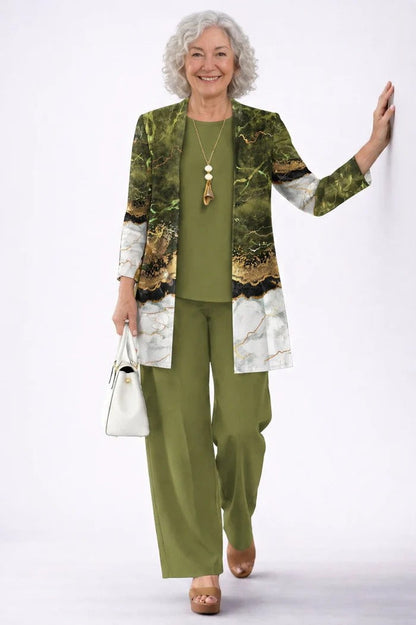 Older model leaning on a wall in the olive set, the open cardigan printed with a green and white marble design with gold veining. 19