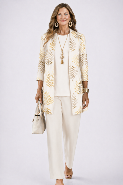 Model wearing the cream set, with gold palm-leaf print on the long open cardigan over a plain top and trousers. 3