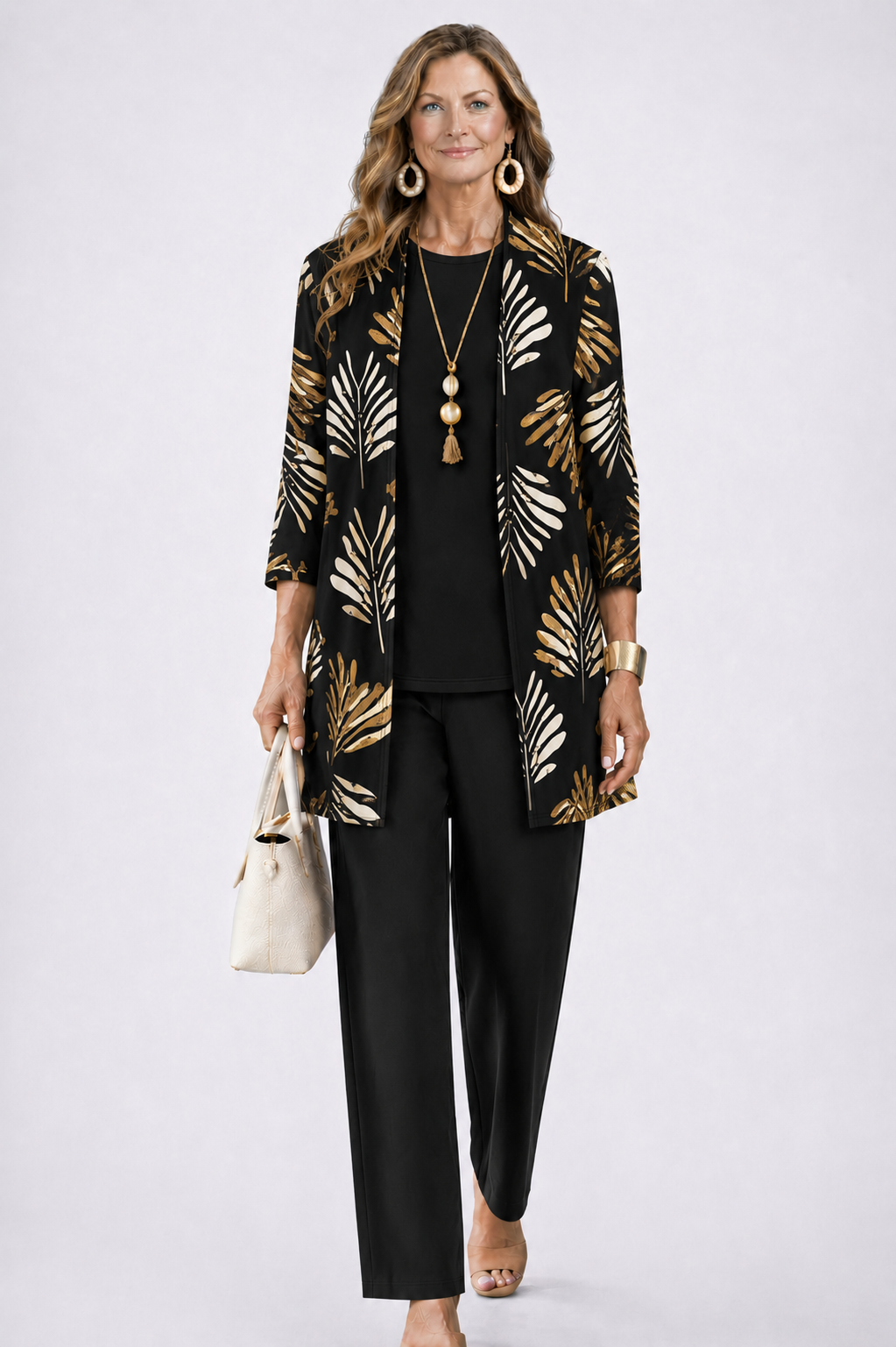 Model wearing the black set, the open cardigan printed with cream and gold palm leaves over a plain black top and trousers. 5
