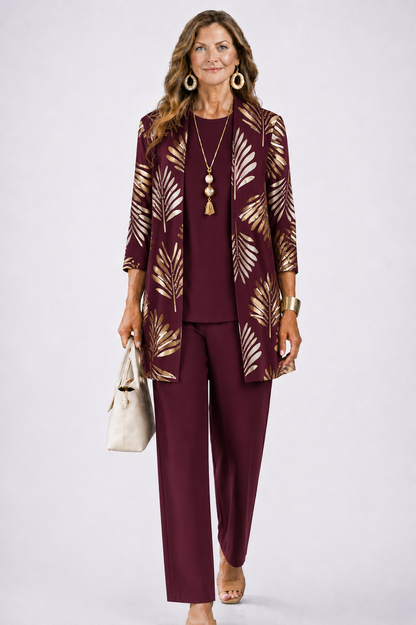 Model in the burgundy set, the open cardigan printed with gold palm leaves over a matching plain top and trousers. 6