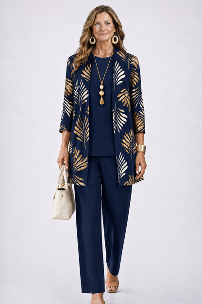 Model wearing the navy set, the open cardigan printed with gold and cream palm leaves over a plain navy top and trousers. 7