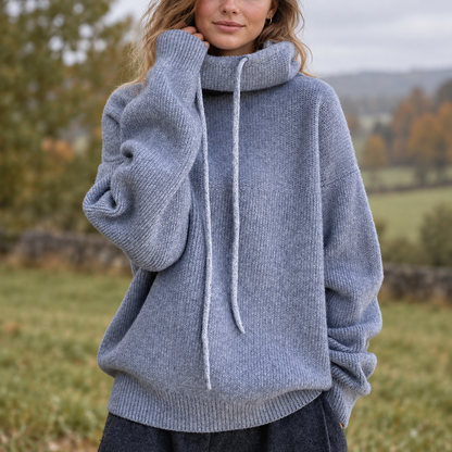 Model in a grey-blue oversized roll neck jumper with drawstrings, standing in an autumn field 1