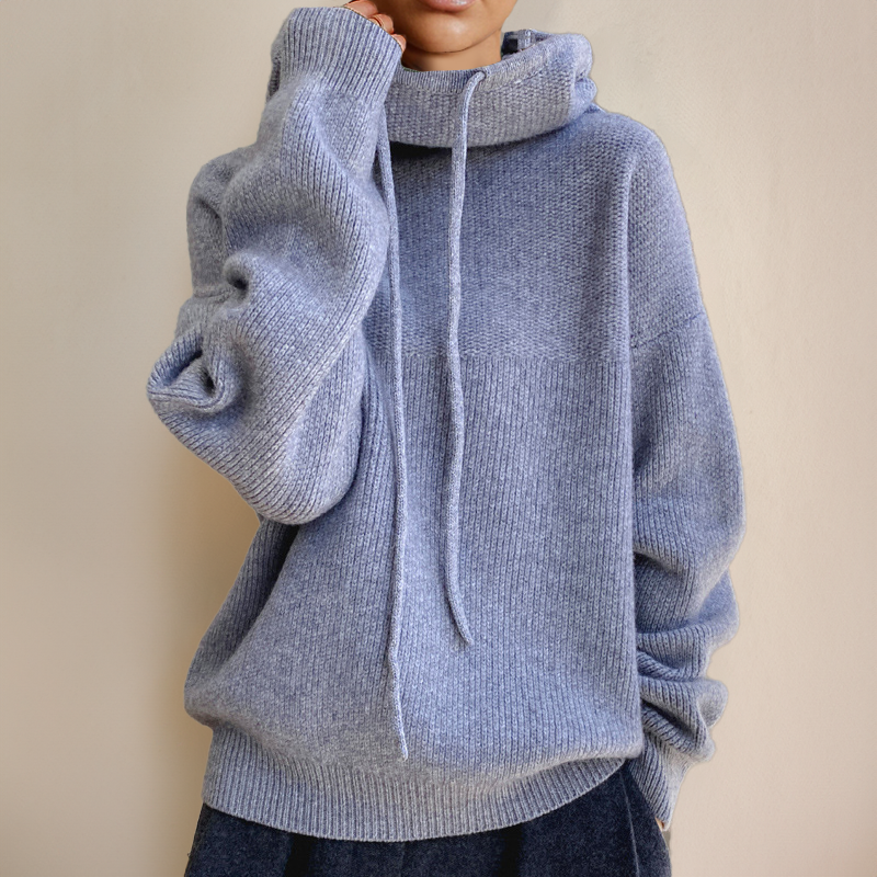 Soft blue-grey jumper on a model with one hand at the cheek, showing the textured knit and drawstrings 6