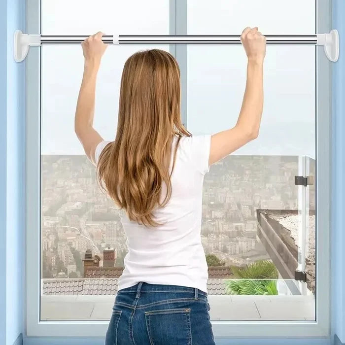 Woman seen from behind lifting the rod into place across a window frame, with a city view beyond. 3