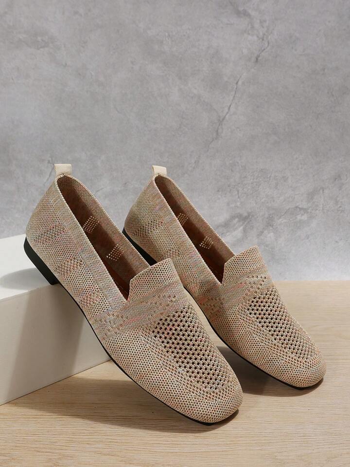 Pair of beige knit slip-on shoes with perforated toes resting against a white block, showing the interior. 7