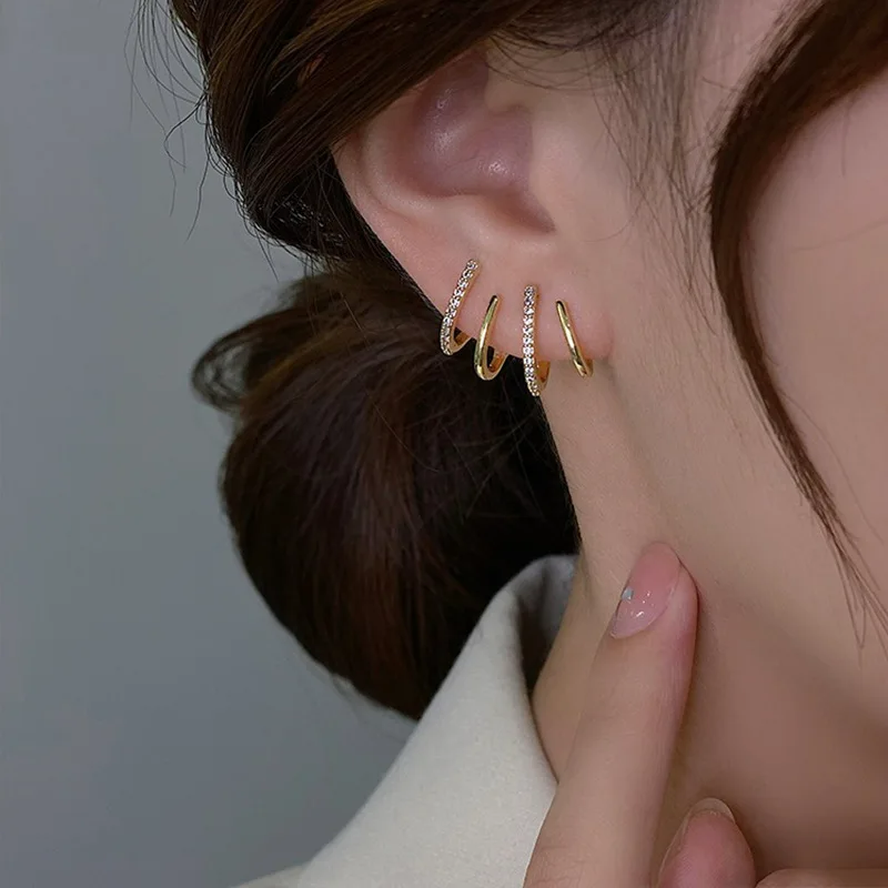 Four-band gold earring with two sparkling stone-set bars, worn on the ear with a hand beside it 5