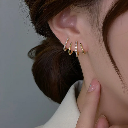 Four-band gold earring with two sparkling stone-set bars, worn on the ear with a hand beside it 5