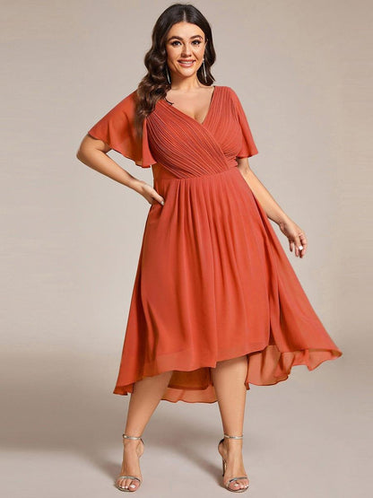 Plus-size model in the burnt orange chiffon dress with flutter sleeves and pleated bodice, skirt swishing as she poses. 97