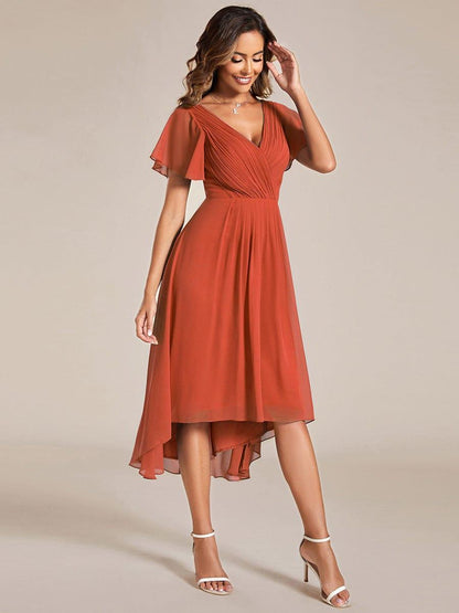 Burnt orange chiffon dress on a smiling model, side-on pose showing the pleated waist and flowing high-low skirt. 96