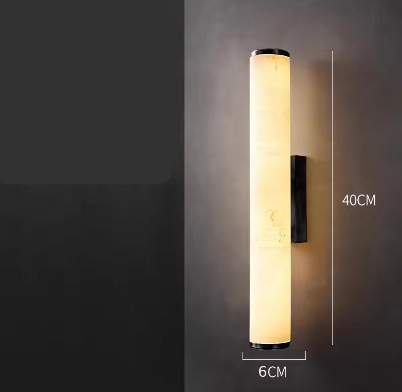 Shorter version of the lit cylindrical marble wall light on a grey wall, with dimension lines marking its height and width. 22