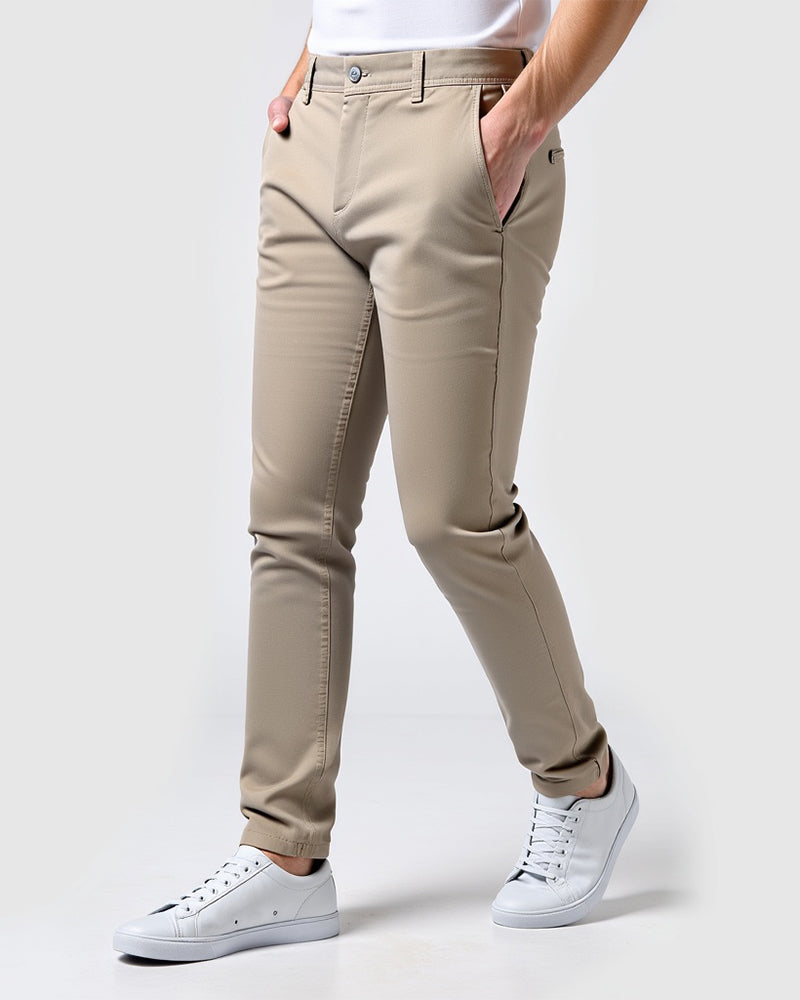 Beige slim chinos seen from the side on a model with a white t-shirt and white trainers, hands in pockets. 14