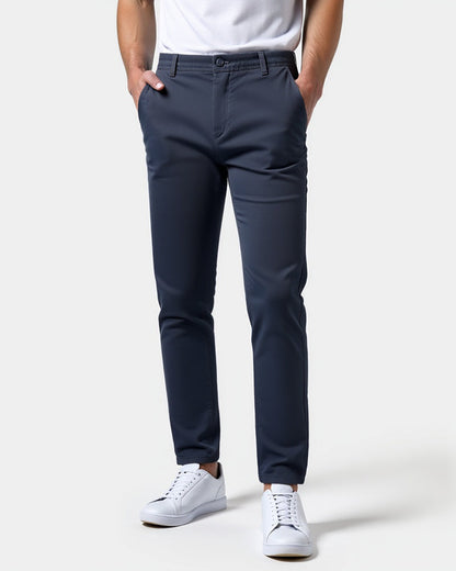 Navy slim chinos worn by a model with a white t-shirt and white trainers, both hands in the front pockets. 15