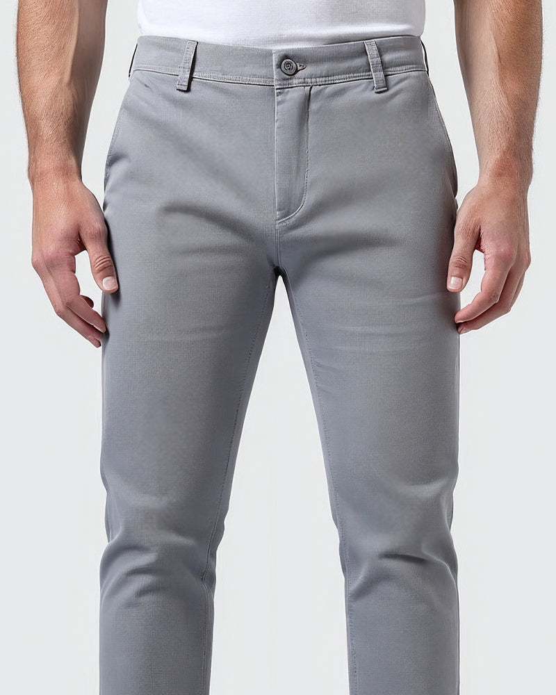Close-up of light grey chinos at the waist, showing the button fastening, fly, belt loops and fabric texture. 5