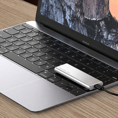 Silver drive resting on a laptop keyboard, connected to the laptop by a black cable 6