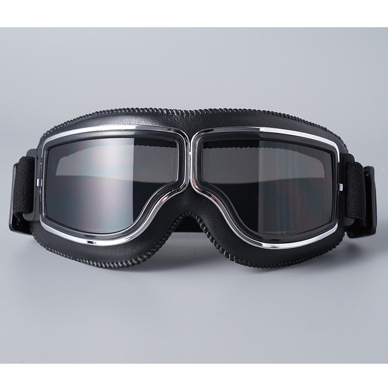 Front view of the black-padded goggles with chrome trim and smoky grey tinted lenses against a grey backdrop. 5