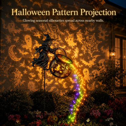 Witch cauldron stake lighting a house wall with projected ghosts, bats, moons and cobwebs, with a lit pumpkin beneath. 4