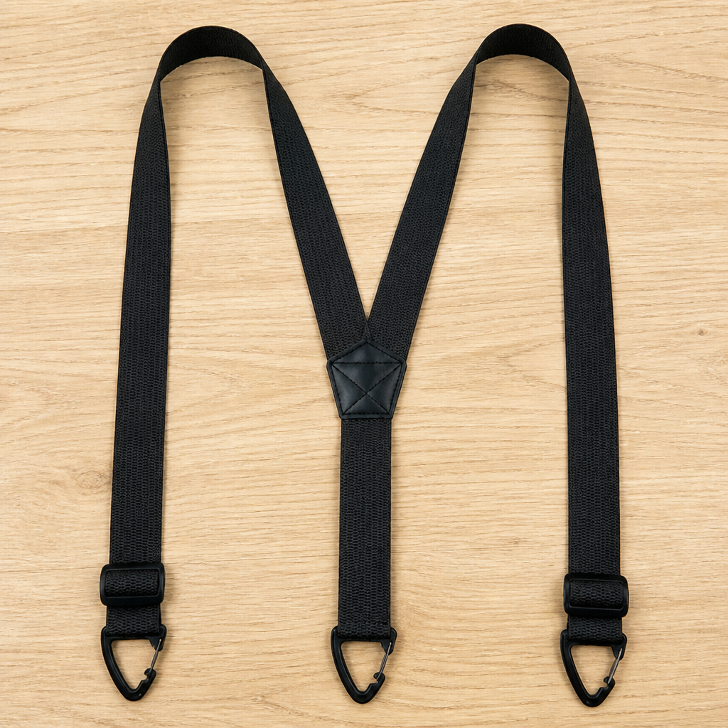 Black Y-back suspenders laid flat on light wood, with the adjusters sitting just above the triangular clips. 13