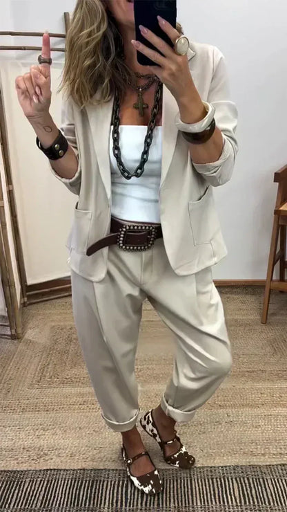 Mirror selfie of the pale beige blazer and matching loose trousers with turned-up hems, worn with a white top and chunky chain necklace. 2