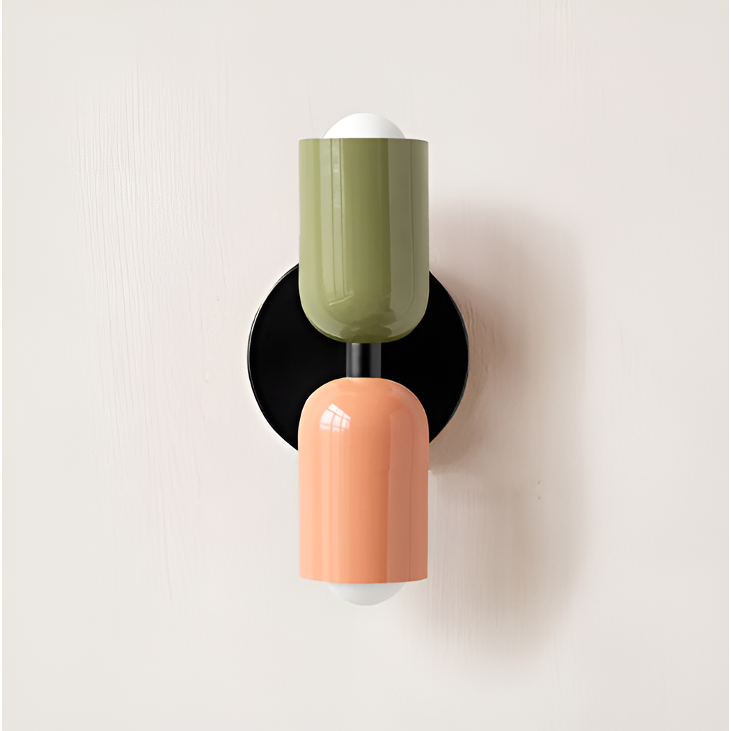 Close front view of a wall light with a green upper head and peach lower head on a black backplate. 20