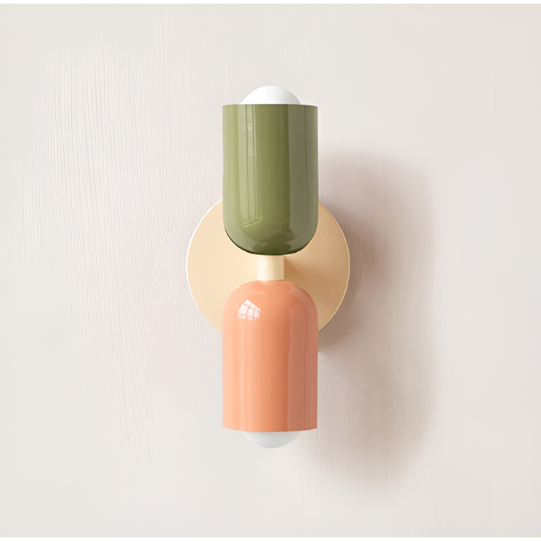 Close front view of a wall light with a green upper head and peach lower head on a cream backplate. 14